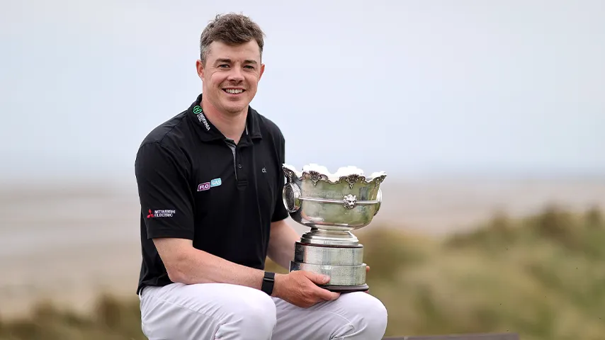 Man Holding Golf Trophy Sitting in front of Beach